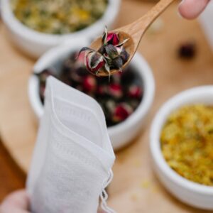 Filtro de papel para té a granel junto a cuencos con hojas y flores secas
